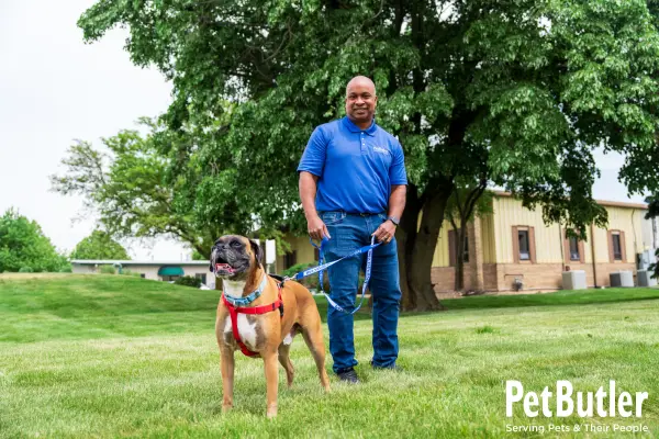Pet Butler employee standing with dog outside smiling at camera